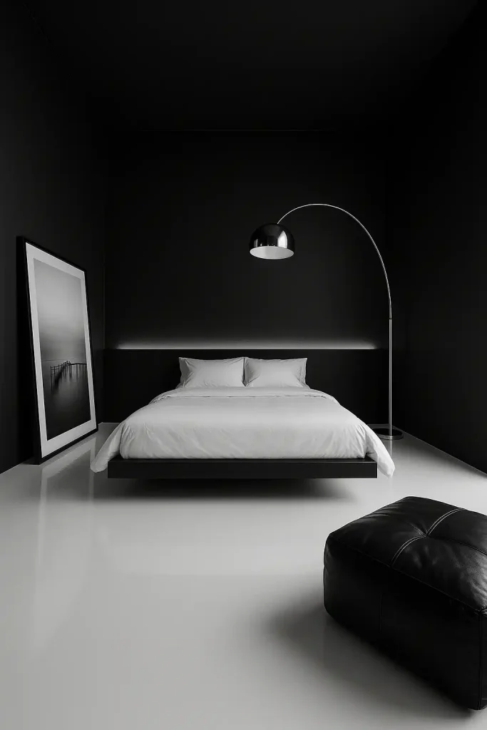 8 × 9 ft monochrome bedroom, matte jet‑black walls, glossy white epoxy floor, floating bed wrapped in crisp white percale, oversized black‑frame photography leaning against wall, chrome arc floor lamp, black leather pouf, linear LED uplighting behind bed, ultra‑wide 12 mm, stark architectural composition.